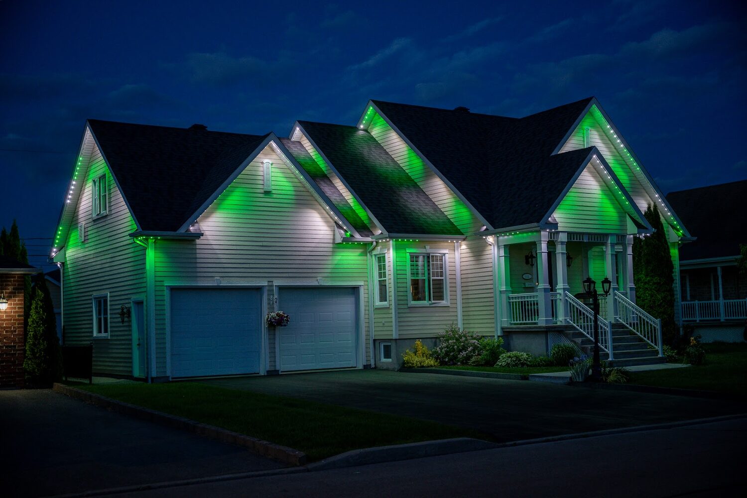 Home lit in green with white accents on the gables