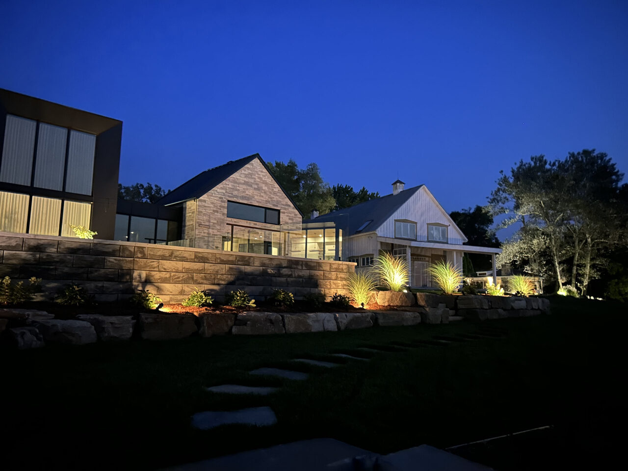 Terraced garden and home lit with landscape spots at dusk