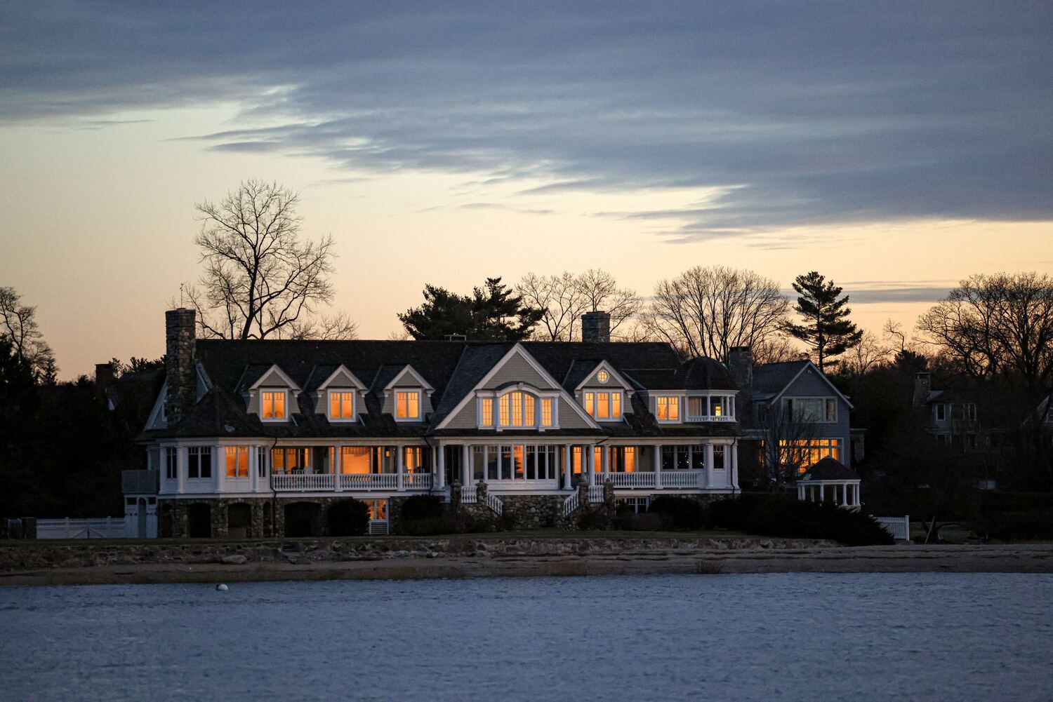 Waterfront home at twilight with windows glowing